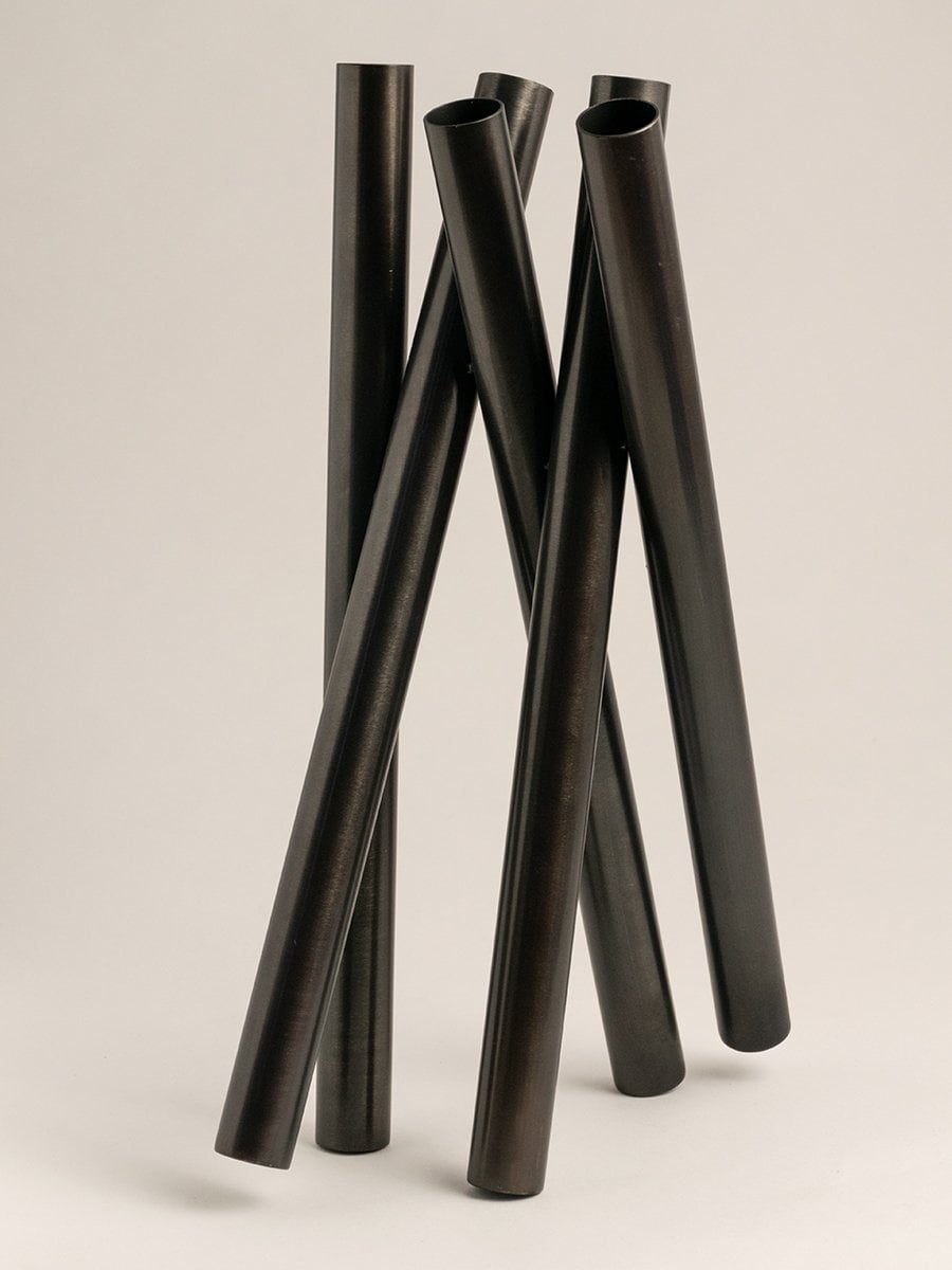 Matte black metal vase with tubular shape on a white background creating a minimalist and contemporary appeal.