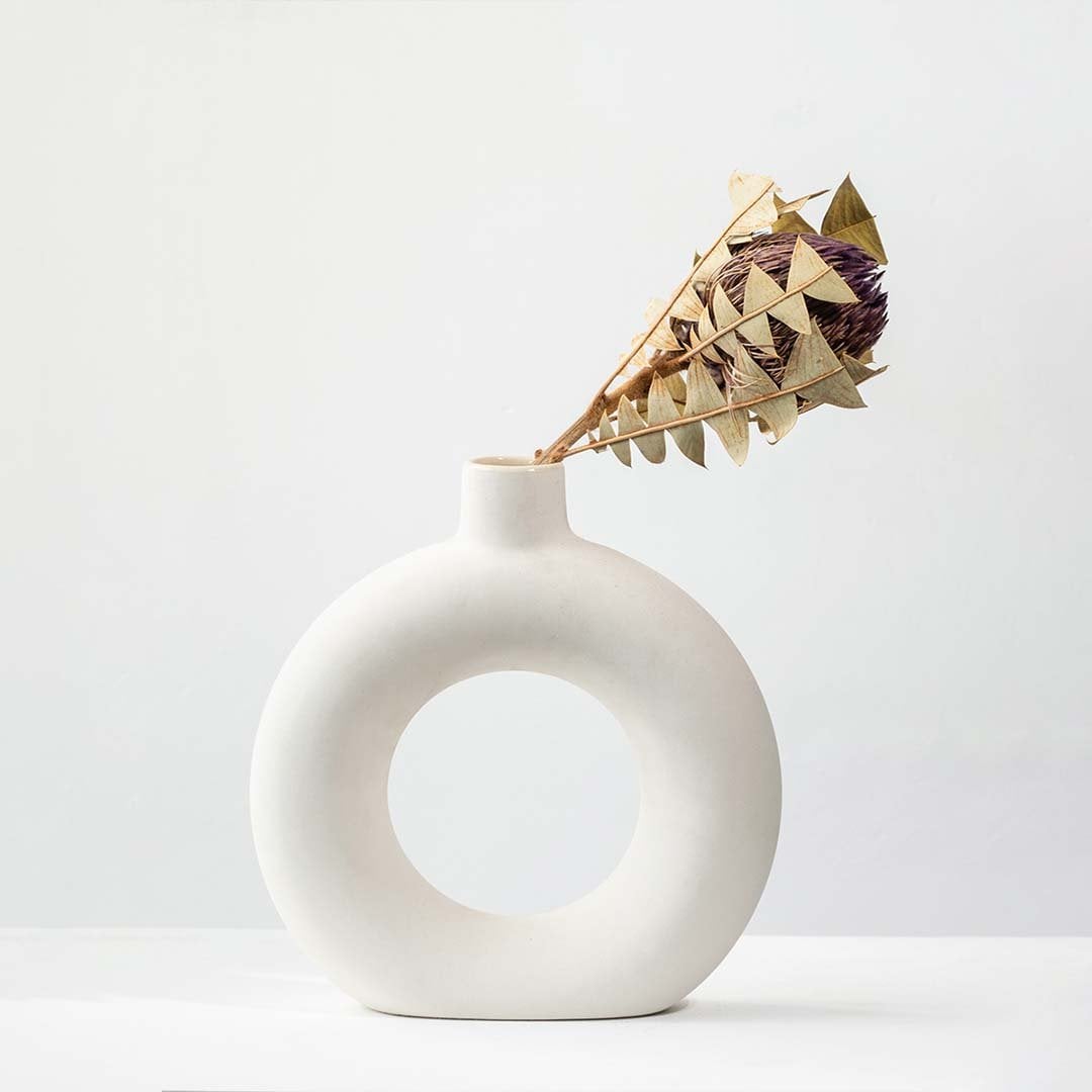 Modern ceramic ring vase in matte white finish styled with dried floral stem on white background for minimalist home Decor accent.