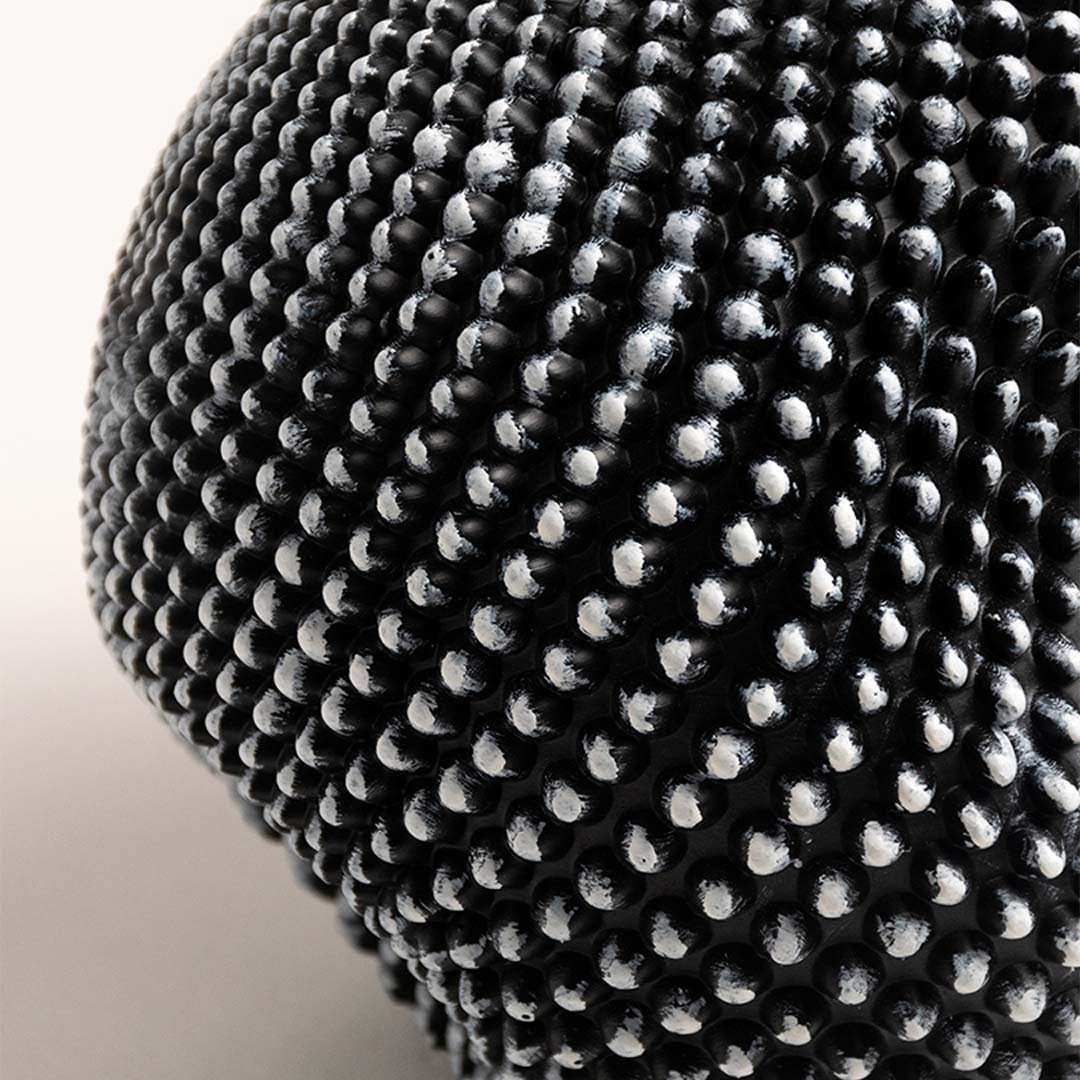 Closeup showing the detailed texture of the black and white sphere sculpture with intricate design.