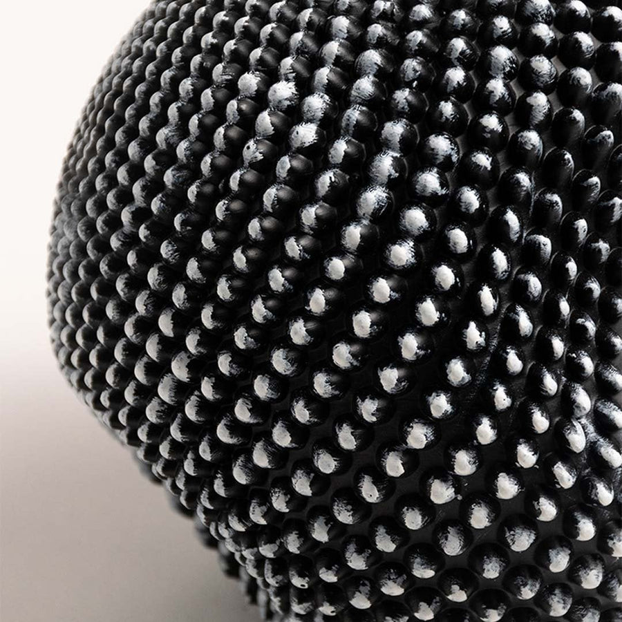 Closeup showing the detailed texture of the black and white sphere sculpture with intricate design.