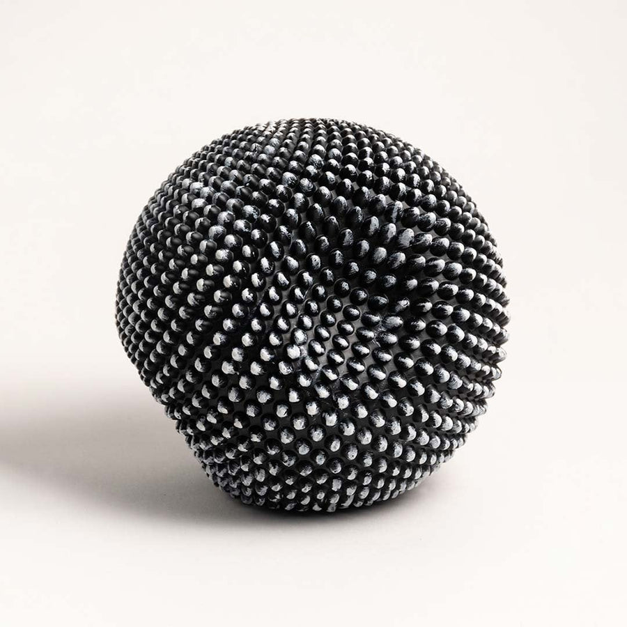 Sleek black and white textured sphere sculpture displayed against a plain white background highlighting its design.