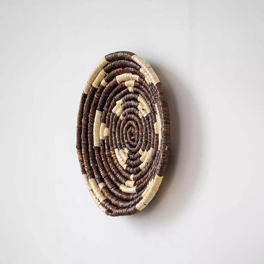 Side view of brown handwoven wall basket showing thickness texture and handwoven depth.