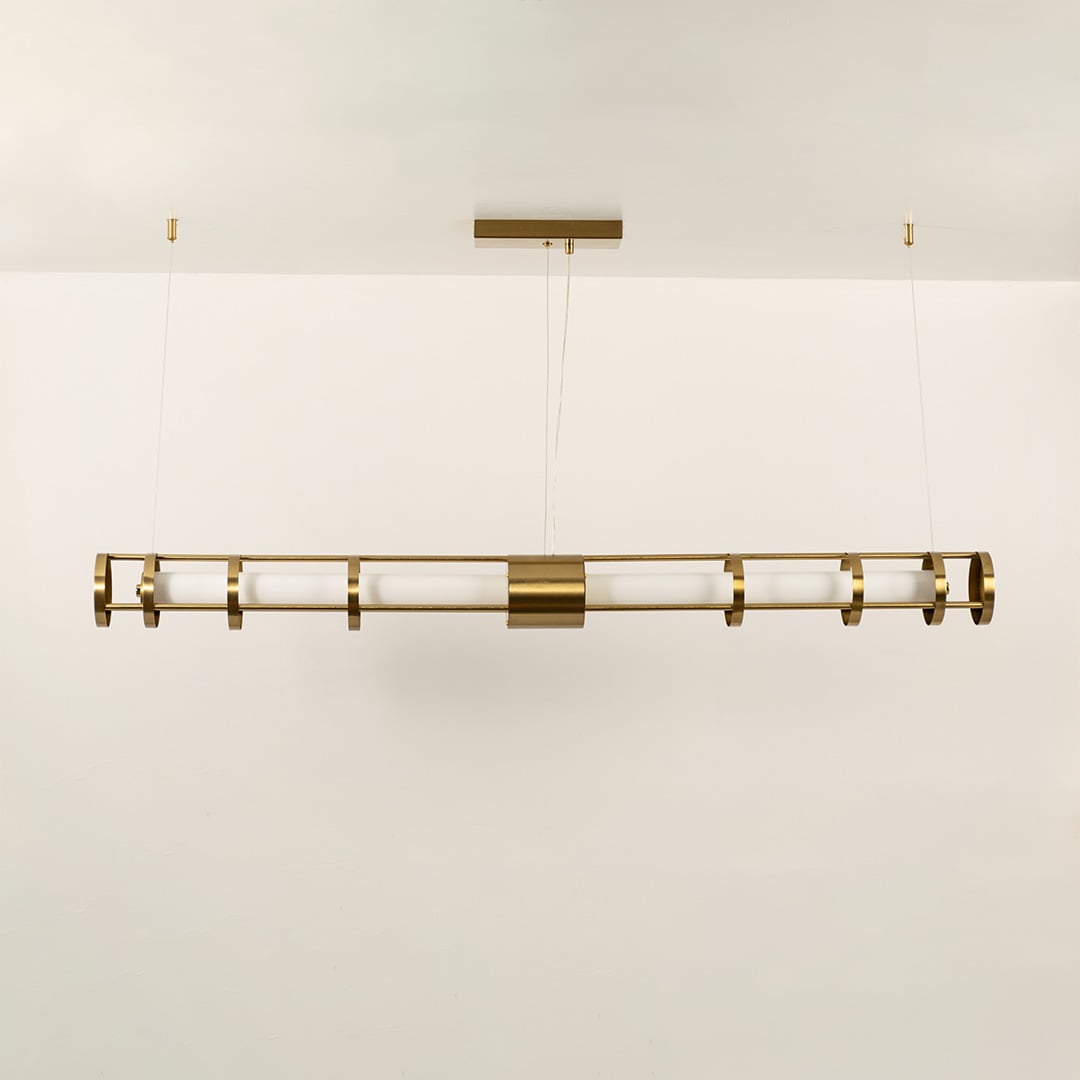A gold linear ceiling fixture with symmetrical cylindrical elements ideal for modern LED chandelier lighting and luxury designer interior décor applications.