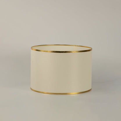 White round drum lamp shade with gold trim shown in close up view on plain background for elegant modern lighting décor.