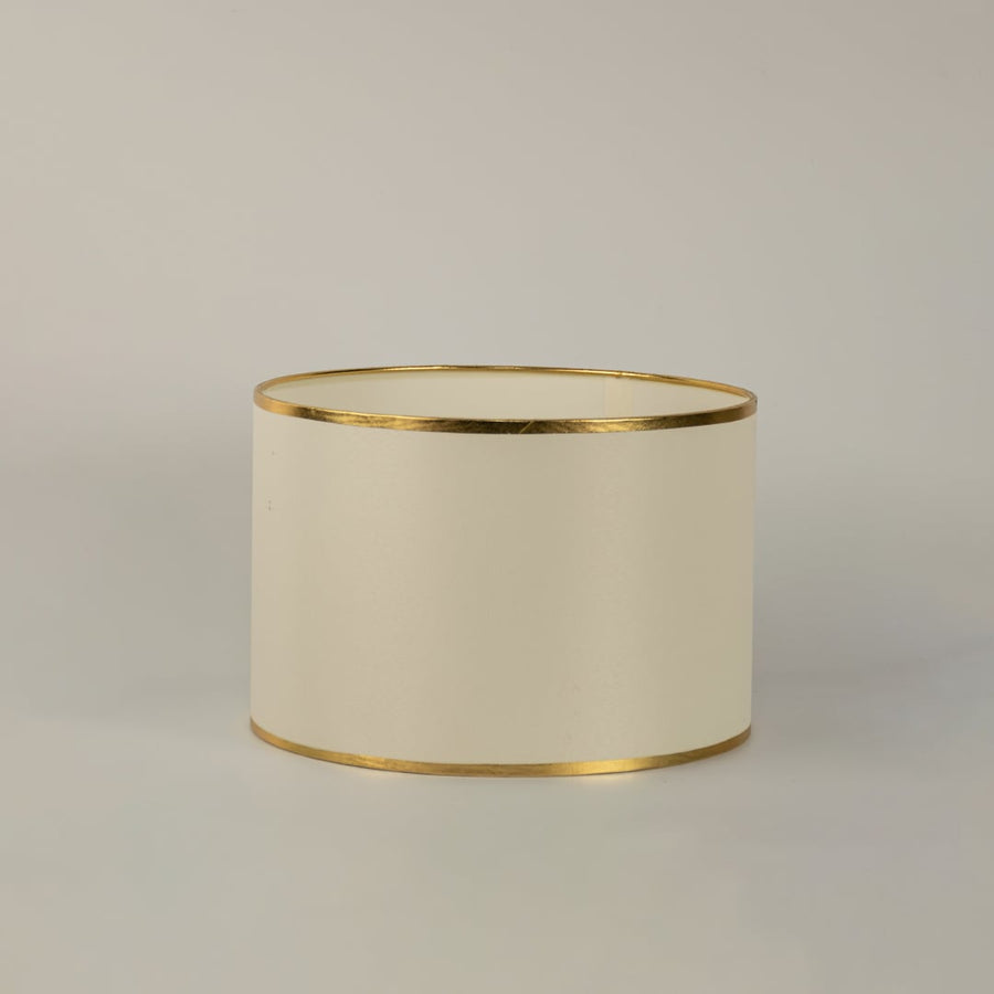 White round drum lamp shade with gold trim shown in close up view on plain background for elegant modern lighting décor.