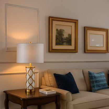White and gold ceramic table lamp with fabric shade placed on wooden console for elegant living room decor styling.