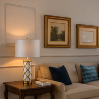 White and gold ceramic table lamp with fabric shade placed on wooden console for elegant living room decor styling.