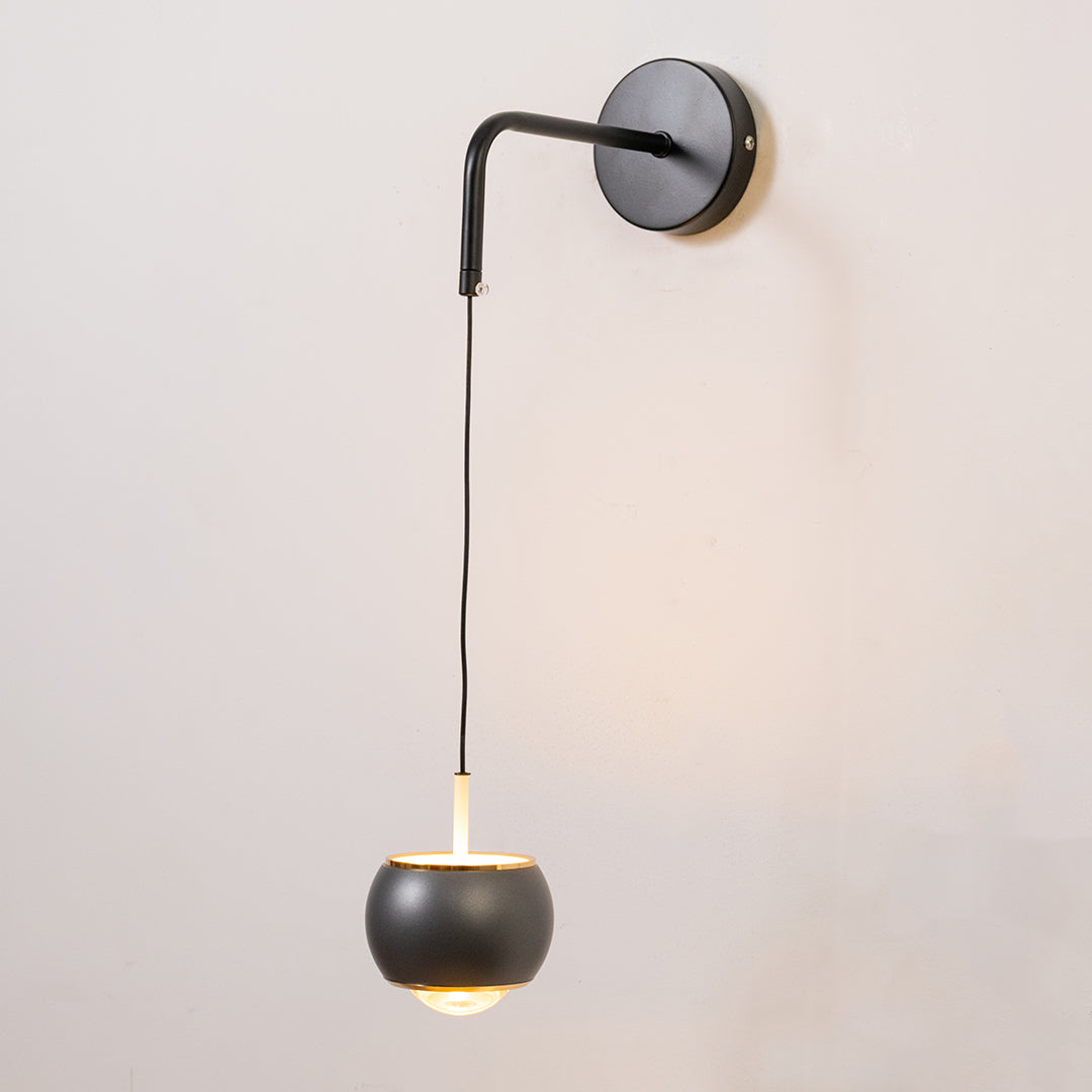 Contemporary wall light in black metal finish with hanging globe shade for bedroom or living decor lighting white background.
