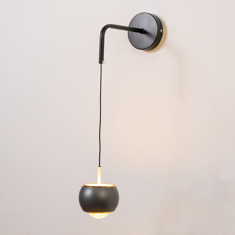 Contemporary wall light in black metal finish with hanging globe shade for bedroom or living decor lighting white background.