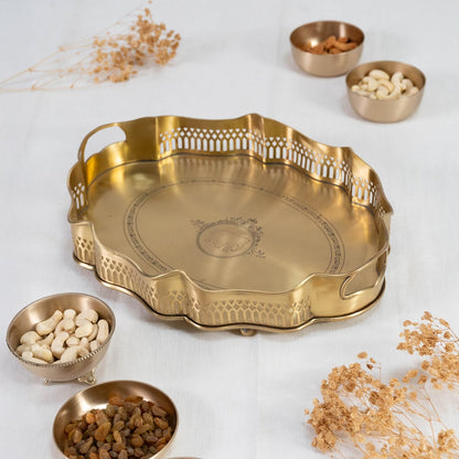 Gold brass serving tray with wavy rim cutwork border and engraved base displayed on plain white background.