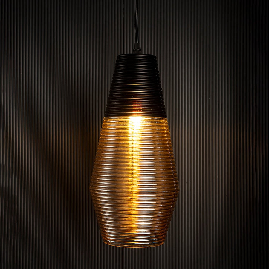 Amber glass pendant lamp glowing warmly on black background adding luxury and depth to modern interior lighting.