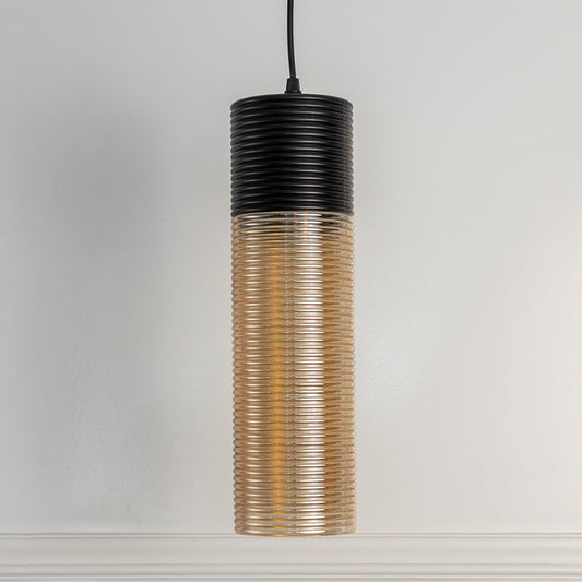 Cylindrical pendant light turned off  with black ribbed top and amber glass body isolated on a plain clean white background.