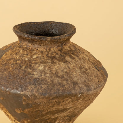 Closeup view of handcrafted ceramic decorative vase showing earthy textured surface with natural brown and grey tones highlighting the artisanal glaze finish.