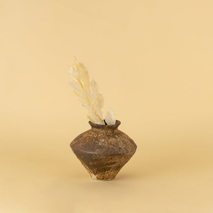 Rustic brown ceramic vase with textured finish styled on wooden table adding earthy elegance to home interior decor