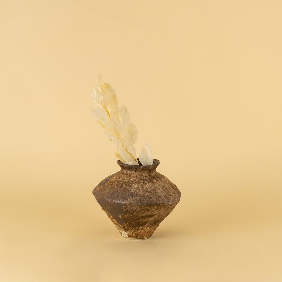 Rustic brown ceramic vase with textured finish styled on wooden table adding earthy elegance to home interior decor