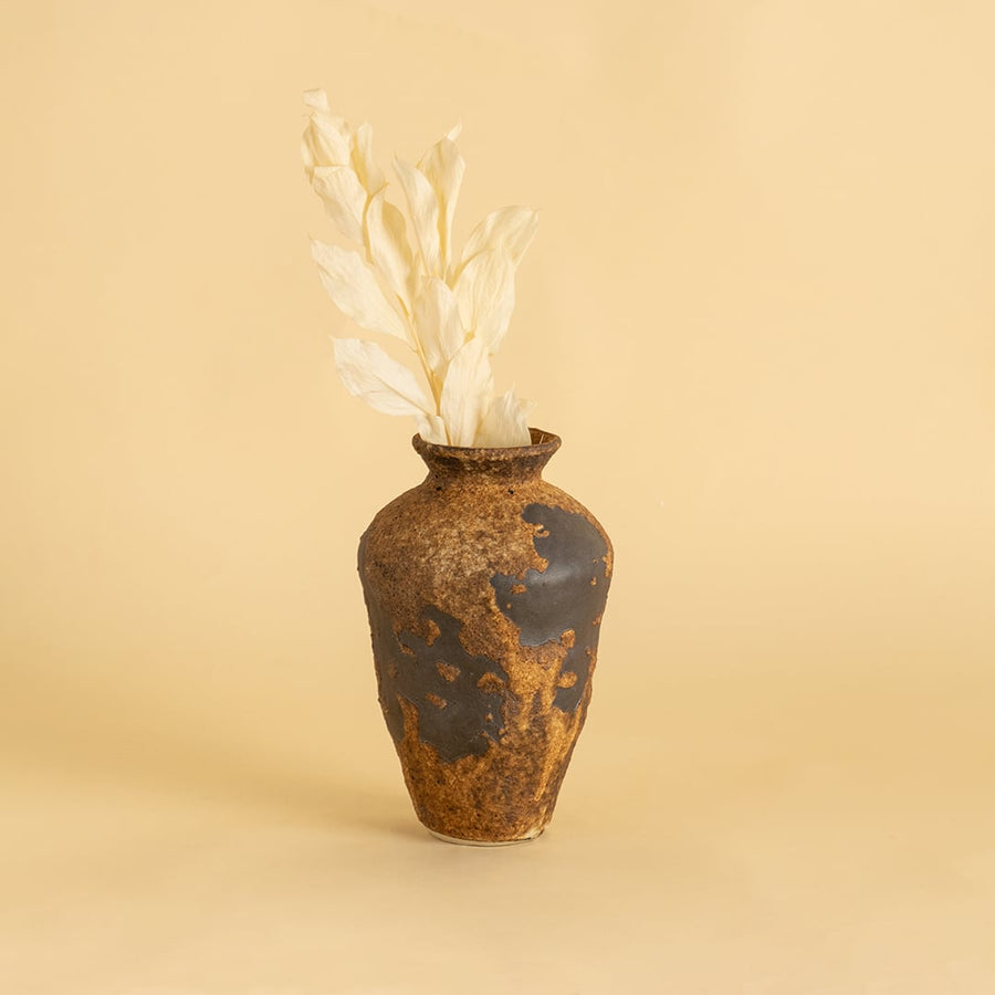 Tall rustic brown ceramic vase with textured finish styled on wooden table adding earthy charm to home interior decor