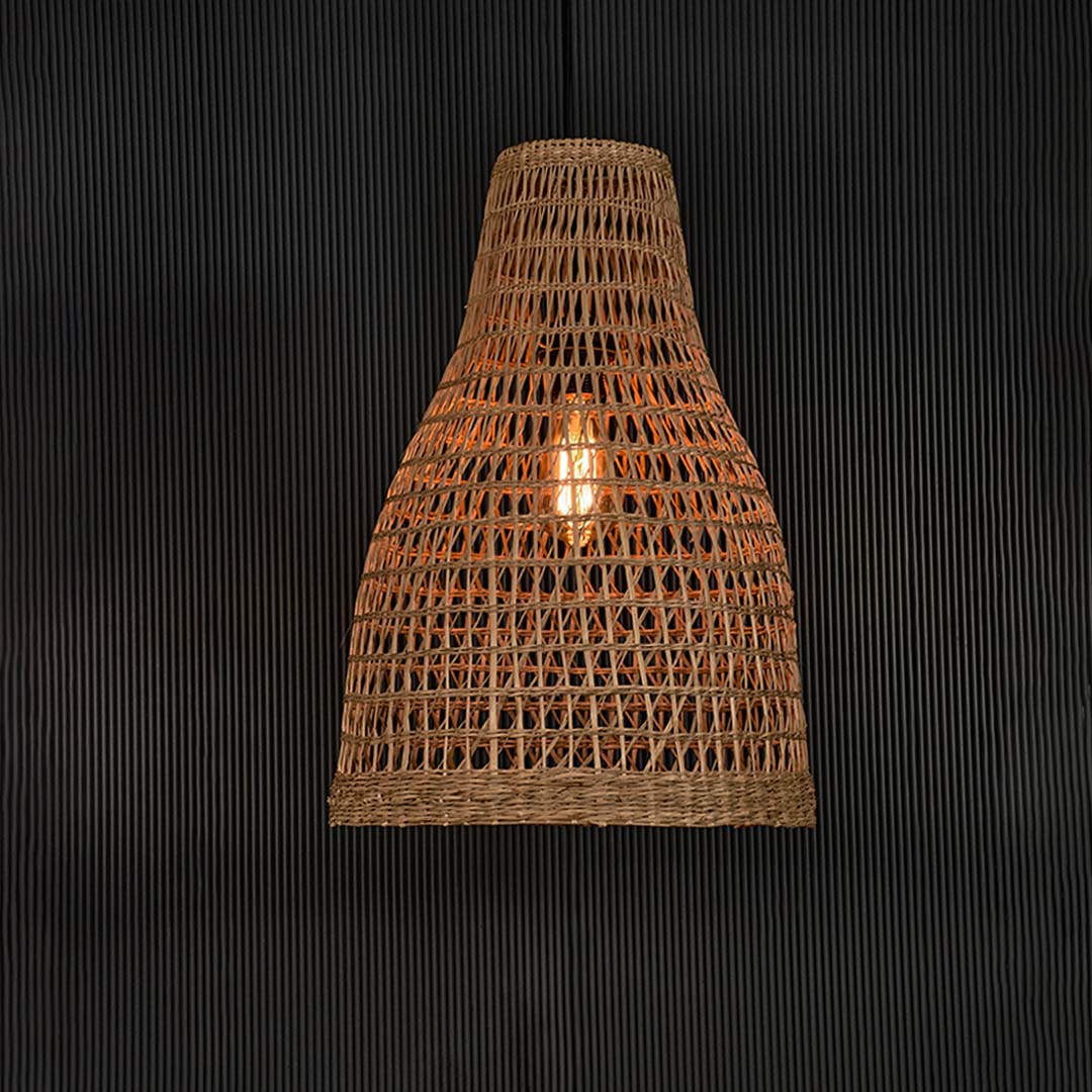 Natural rattan pendant lamp with woven detail illuminated on back background for elegant boho and cafe ceiling decor.