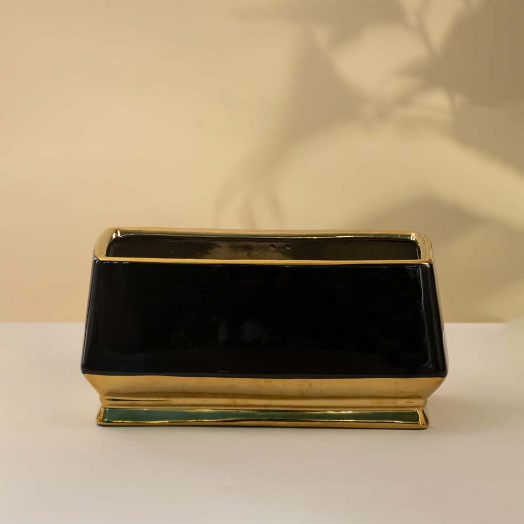 Rectangular black ceramic vase with a glossy finish and golden base placed on a white background adding a touch of modern elegance to the decor.