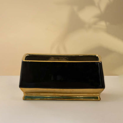 Rectangular black ceramic vase with a glossy finish and golden base placed on a white background adding a touch of modern elegance to the decor.