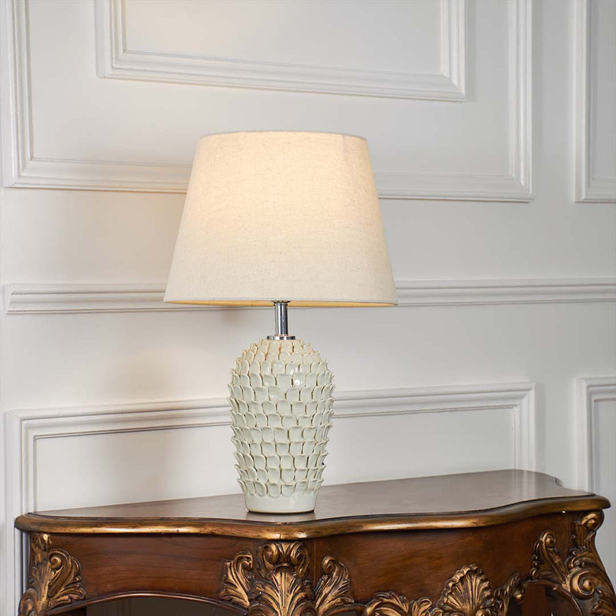 Ceramic table lamp with blue patterns and a glowing light styled on a bright white background creating a clean premium product display.