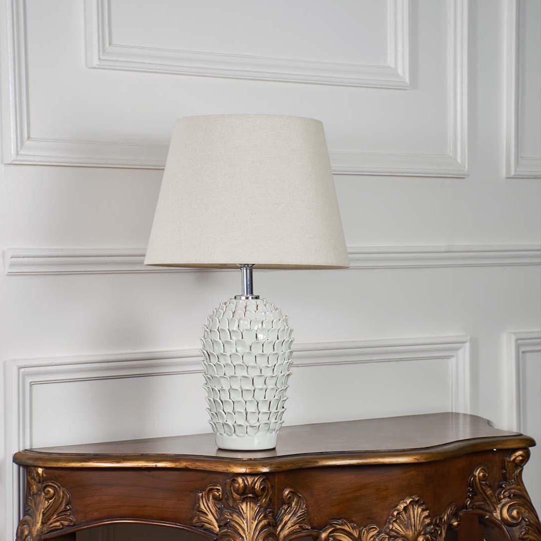 Ceramic table lamp with detailed blue design placed on a white background showcasing its shape and craftsmanship in a soft natural tone.