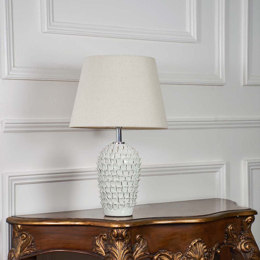Ceramic table lamp with detailed blue design placed on a white background showcasing its shape and craftsmanship in a soft natural tone.
