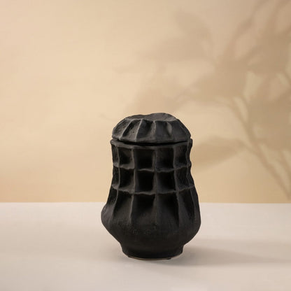 Matte black ceramic vase displayed on a white background highlighting detailed craftsmanship and modern artistic form.