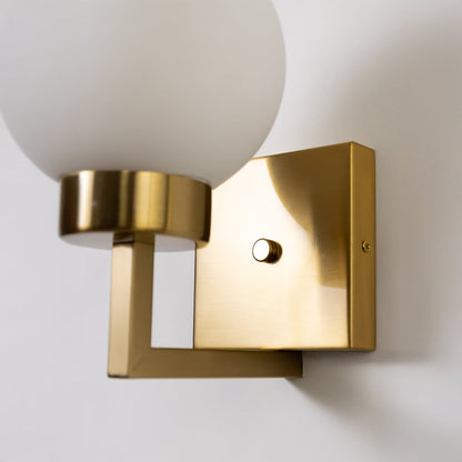 Closeup of gold metal wall light with frosted glass globe shade showing premium detailing for elegant contemporary indoor lighting.