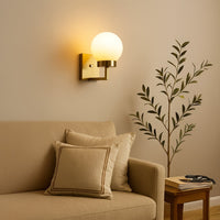 Gold metal wall light with frosted glass globe shade styled in a modern room adding warm ambient lighting for bedrooms hallways and living spaces.
