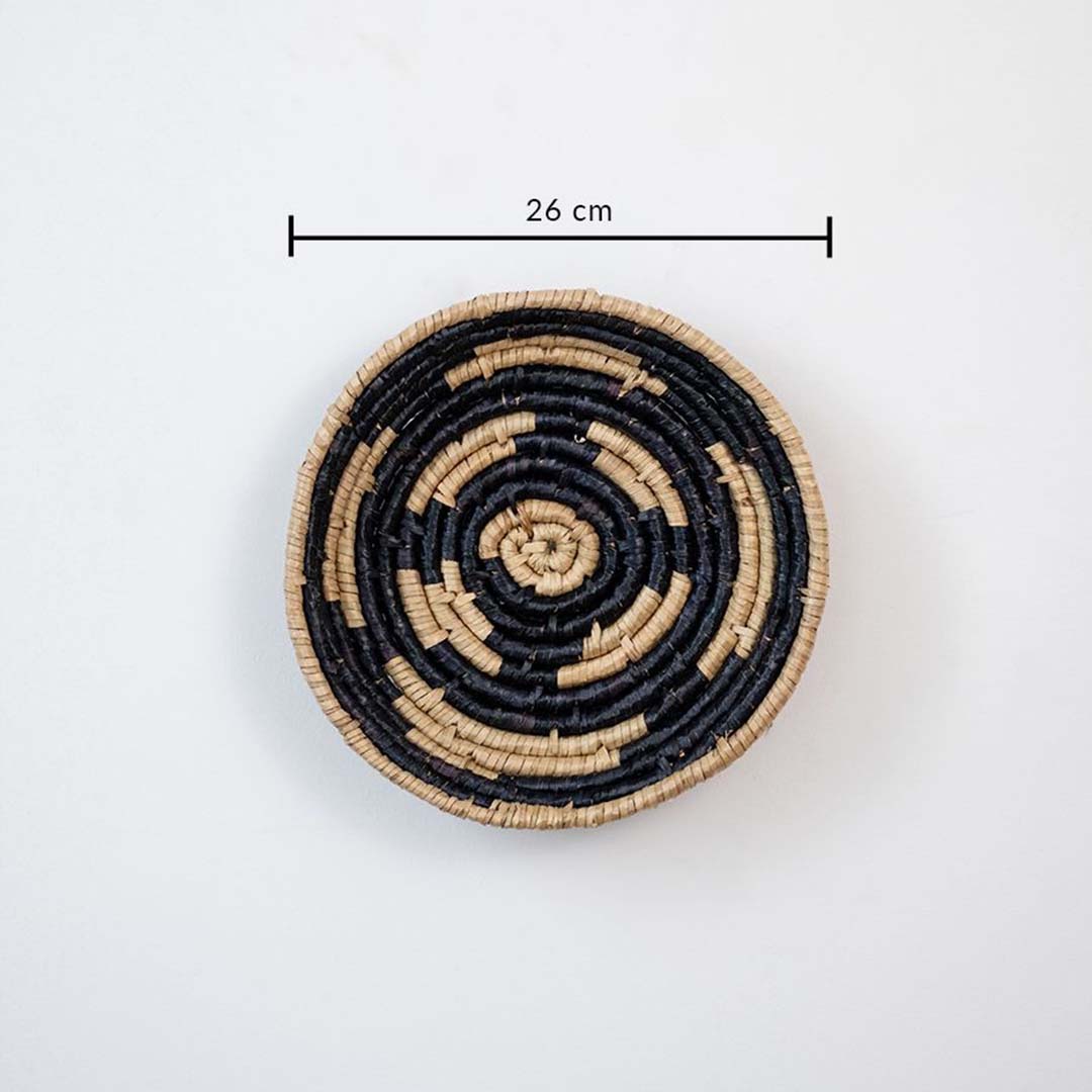 Handwoven wicker wall decor plate 26 cm round in beige and black natural fiber design light off white background with size.