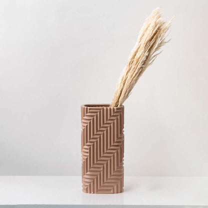 Modern textured ceramic vase in warm beige tone placed on tabletop with dried pampas grass creating minimalist home decor accent.