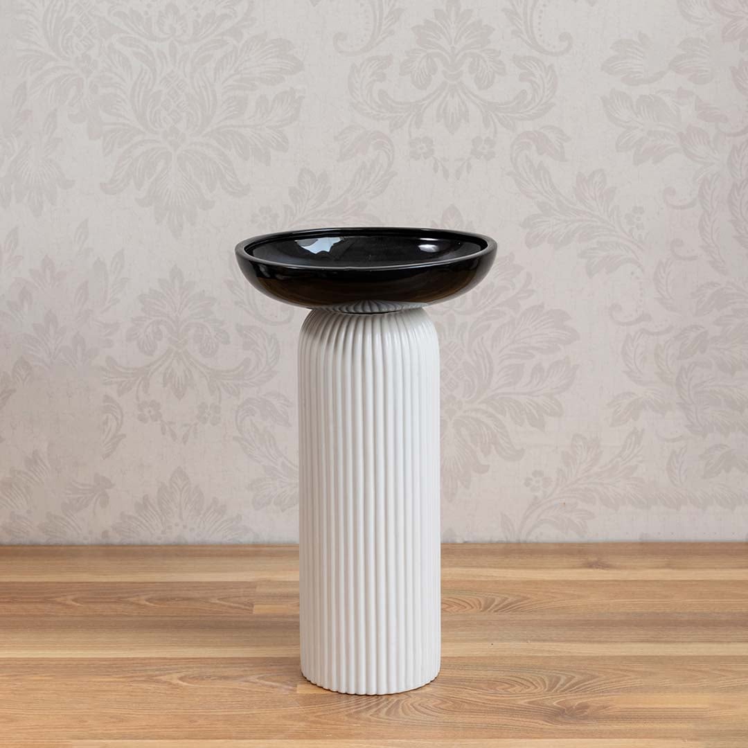 Minimalist white and black ceramic vase with glossy bowl design and ribbed column base on white backdrop.