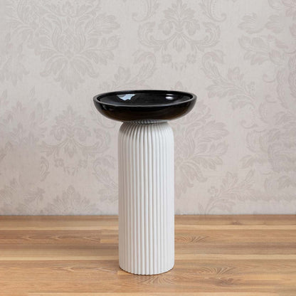 Minimalist white and black ceramic vase with glossy bowl design and ribbed column base on white backdrop.