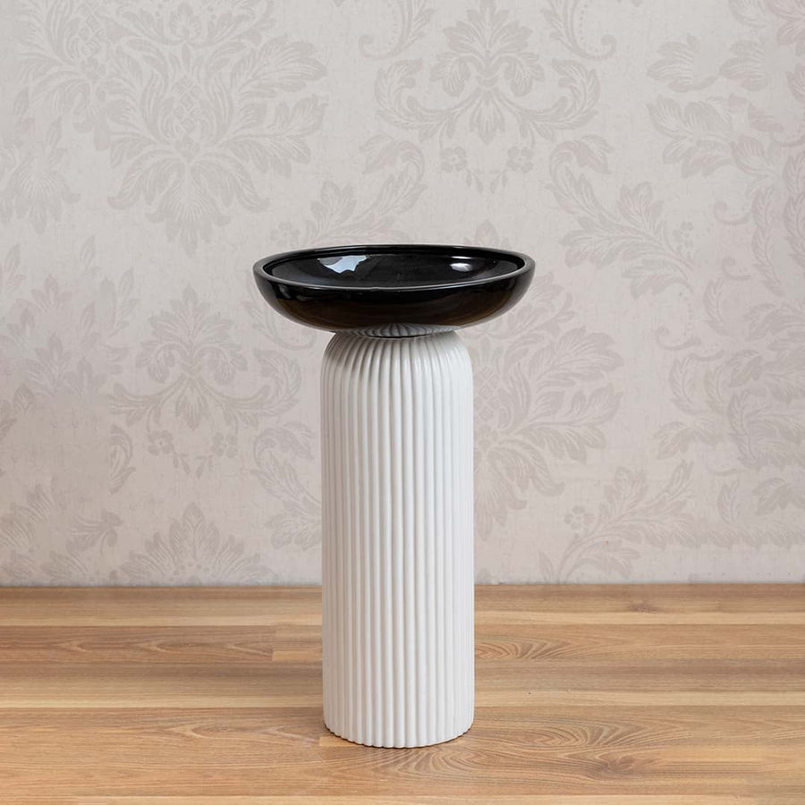 Minimalist white and black ceramic vase with glossy bowl design and ribbed column base on white backdrop.
