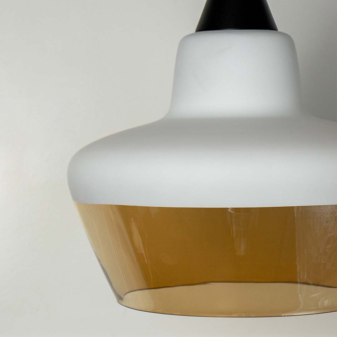 Closeup of contemporary pendant lamp with white and amber glass shade elegant ceiling light for modern home decor.