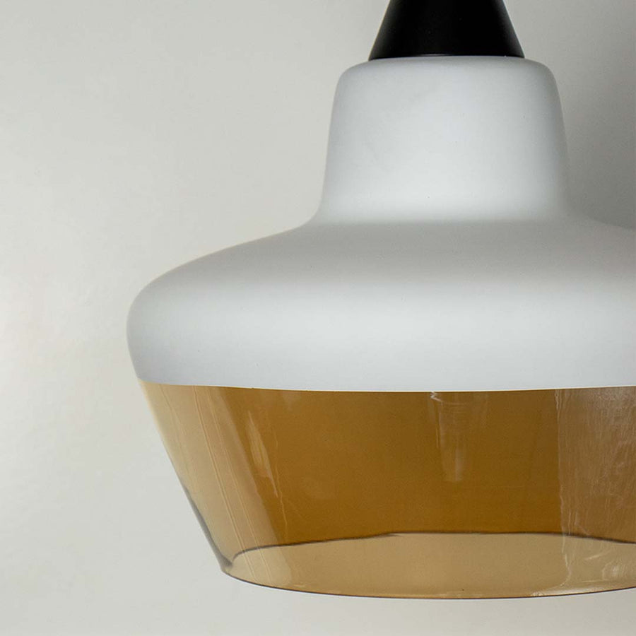 Closeup of contemporary pendant lamp with white and amber glass shade elegant ceiling light for modern home decor.