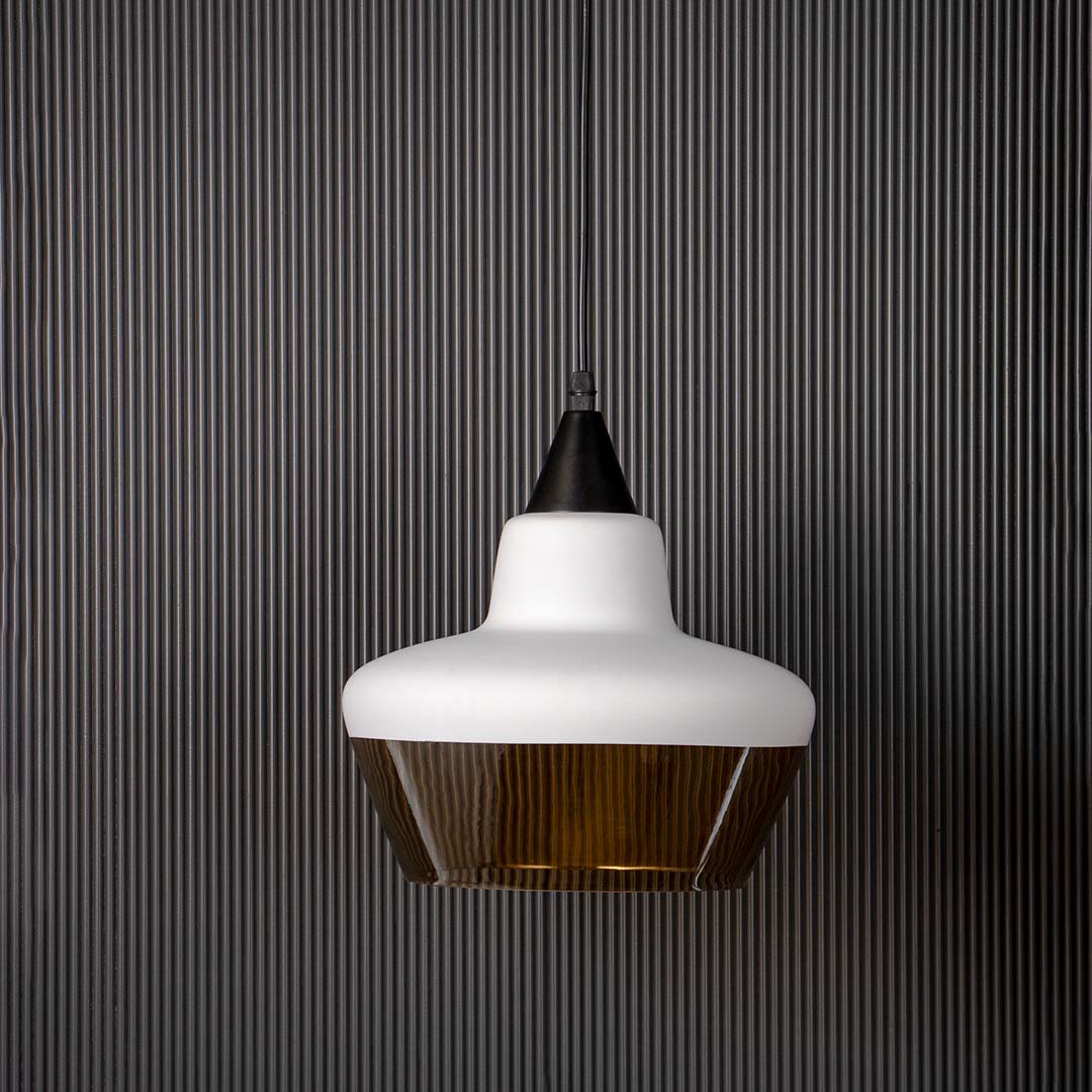 White and amber glass pendant light shown off against black background contemporary ceiling lamp for living interiors.