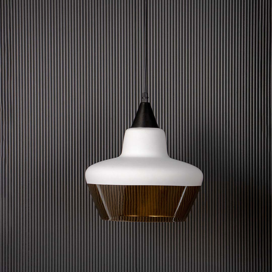 White and amber glass pendant light shown off against black background contemporary ceiling lamp for living interiors.