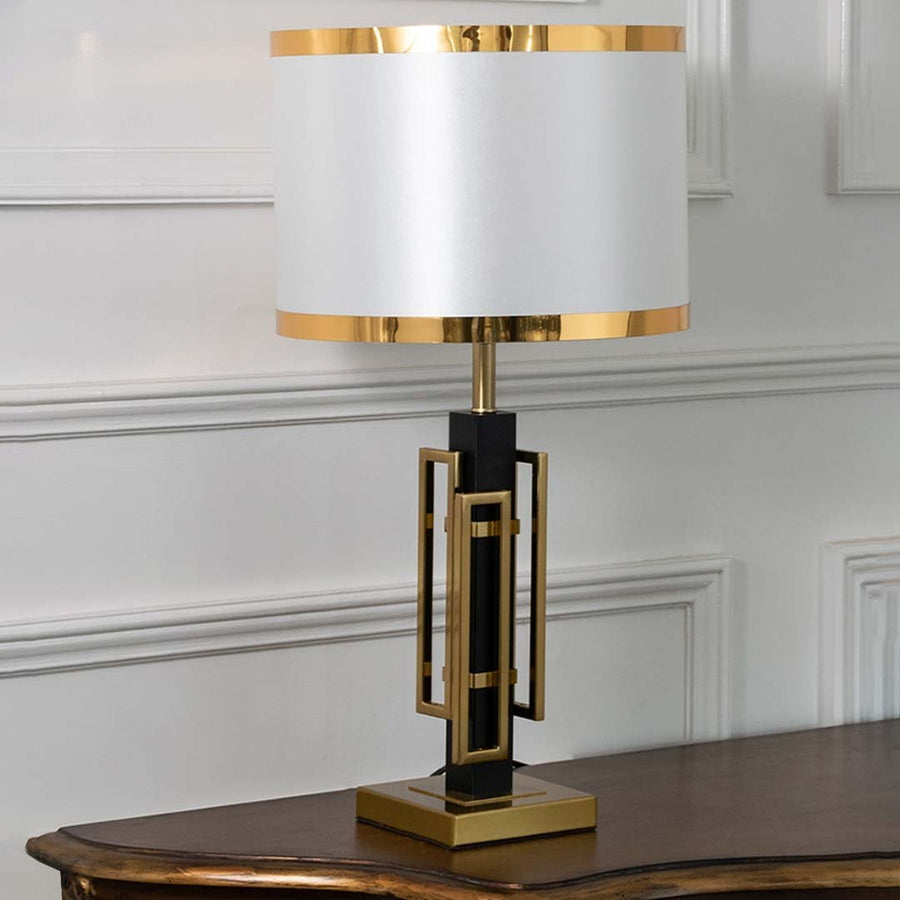 Black and gold geometric table lamp with white drum shade displayed on a white background perfect for modern side table styling and home decor accents.