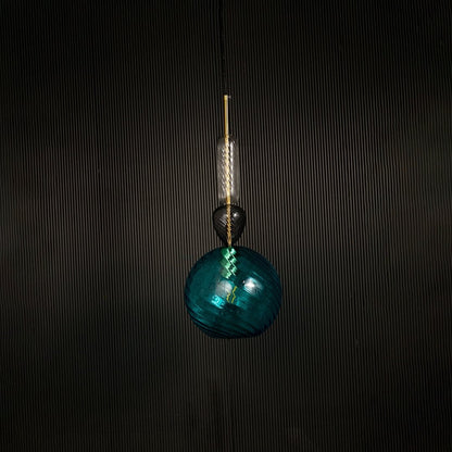 Artistic blue glass pendant light with golden detailing displayed on dark background with light off for elegant modern lighting style.