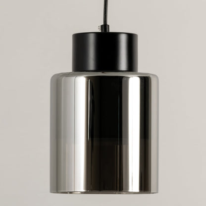 Smoke glass pendant light illuminated to showcase sleek modern ceiling lighting with reflective decorative appeal.