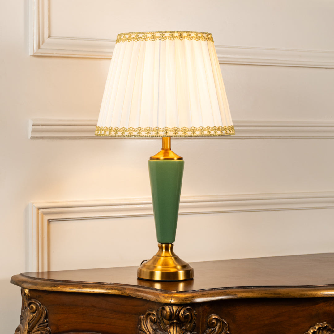 Green ceramic table lamp with fabric shade styled on a wooden console table creating elegant classic ambient lighting.