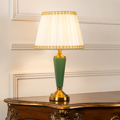 Green ceramic table lamp with fabric shade styled on a wooden console table creating elegant classic ambient lighting.