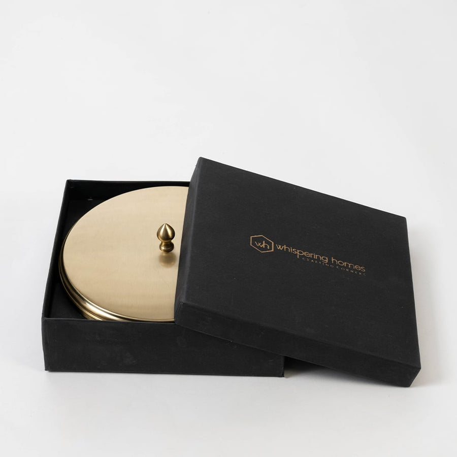 Brass masala box with compartments and a serving spoon shown open with lid leaning beside on white background.