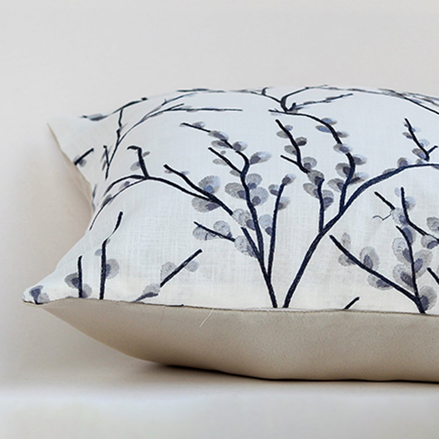 Closeup of the cushion showing the fine stitched grey branches and textured fabric detail.