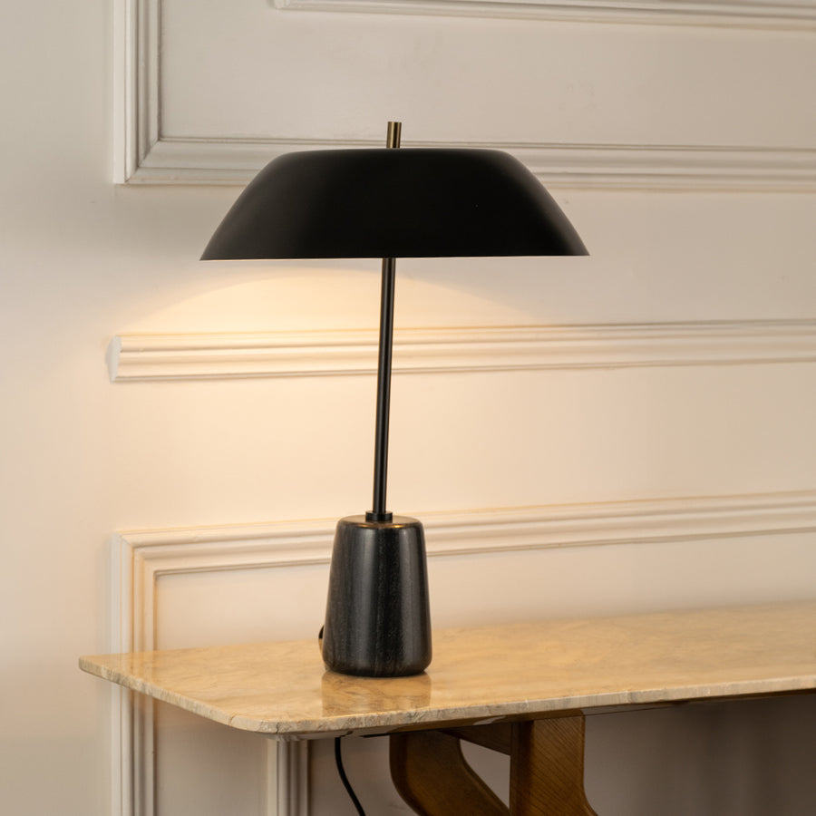 Closeup of table lamp with slim black metal stand and wide shade showing clean lines for modern living room decor placement.