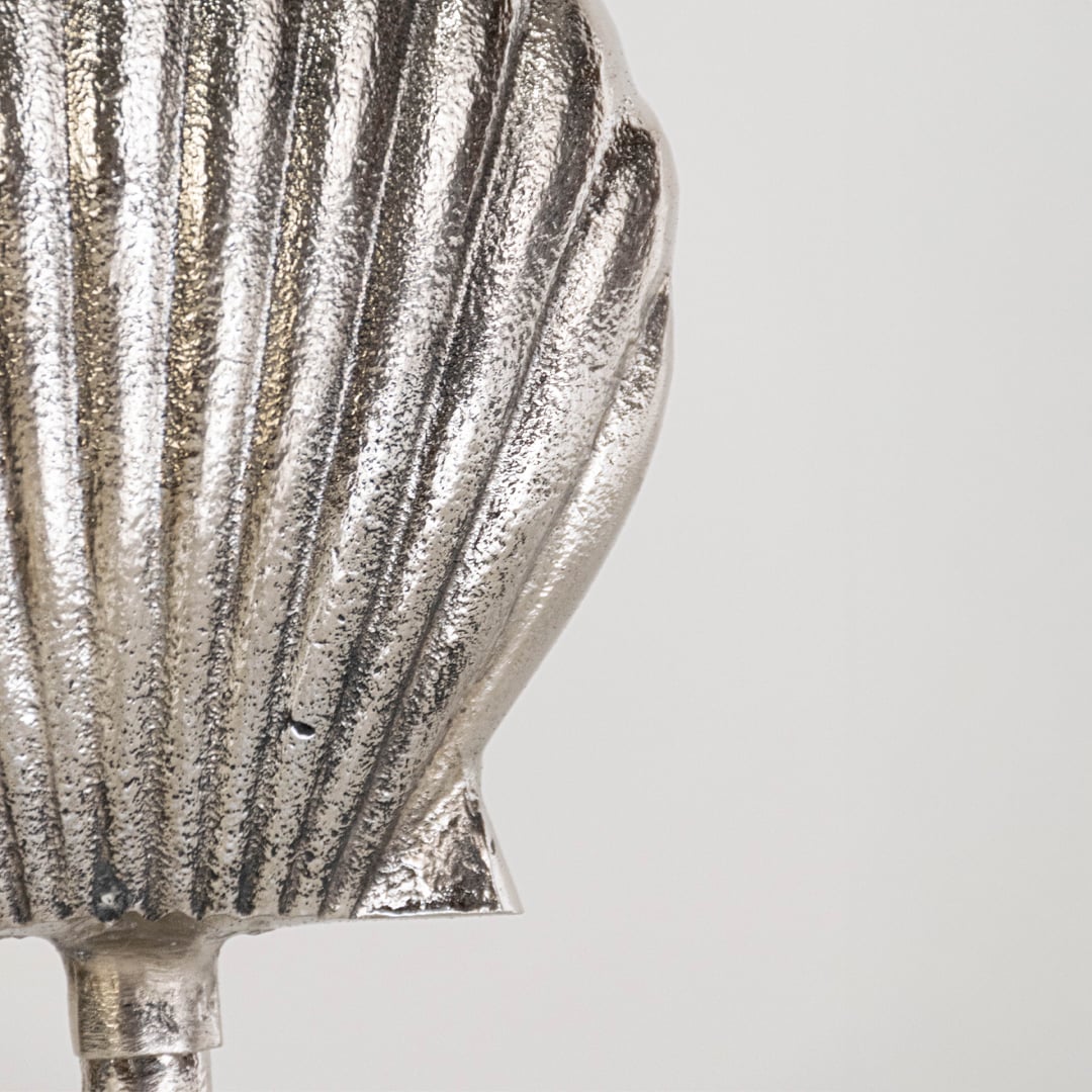 Close view of silver metal seashell decor showing fine texture and sculptural base details in elegant coastal style