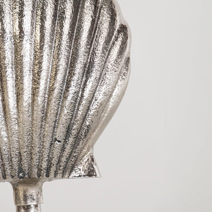 Close view of silver metal seashell decor showing fine texture and sculptural base details in elegant coastal style