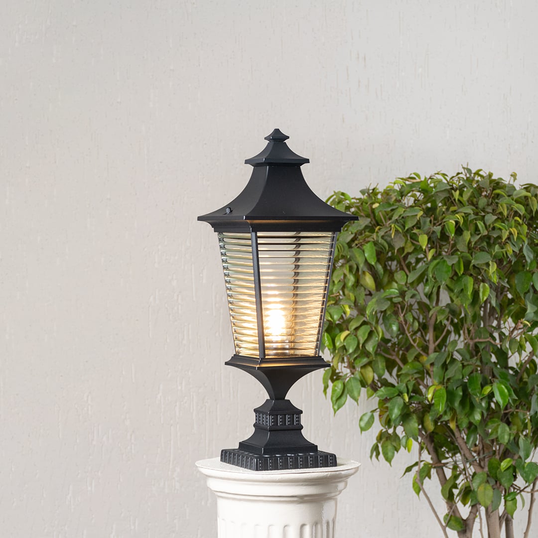 Black pillar light with ribbed glass glowing warmly to enhance outdoor walkways gardens and entrance decor.