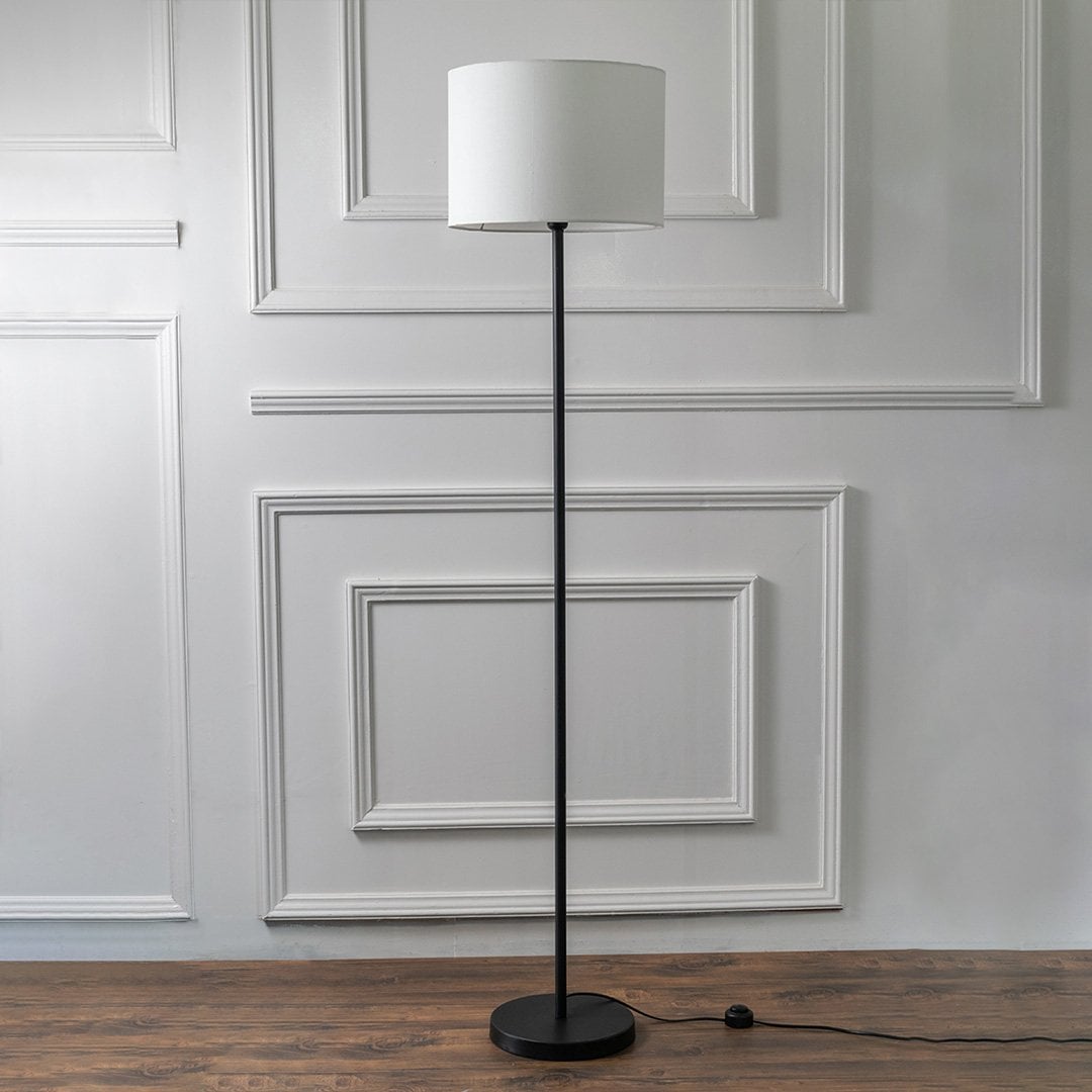 Modern floor lamp with black stand and white fabric lampshade on a plain white background – minimalist home lighting